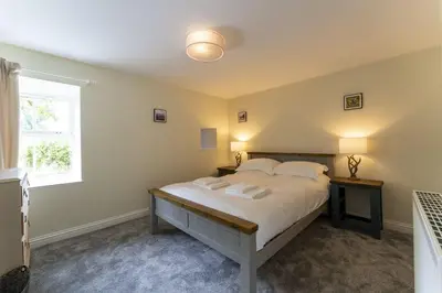 a bedroom with a large bed with two tables and a window at Garden Cottage in Gargunnock