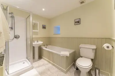 a bathroom with a toilet and a tub and a sink at Garden Cottage in Gargunnock