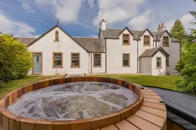 an outdoor hot tub in front of a house at Rachel's Farm luxury escapes with Hots Tubs in Buchlyvie