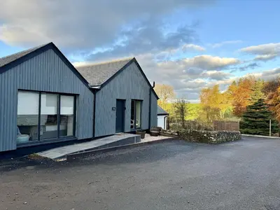 a blue house with a driveway in front of it at Rachel's Farm luxury escapes with Hots Tubs in Buchlyvie