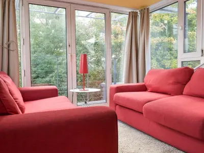 a living room with a red couch and windows at Tigh Nam Muc in Loanhead