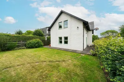 a white house with a yard at Earnside Cottage in Comrie