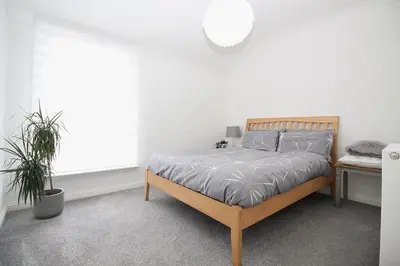 a white bedroom with a bed and a window at Katie's house in Cumbernauld