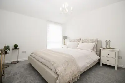 a white bedroom with a large bed and a window at Katie's house in Cumbernauld