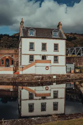 a house with its reflection in a body of water at Custom House Hotel in Bowling