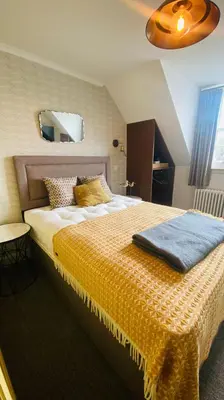 a bedroom with a large bed with a blue blanket on it at Custom House Hotel in Bowling