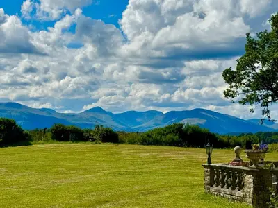 a field of green grass with mountains in the background at FINN VILLAGE Loch Lomond Villa - THE BLACK ROOM with Private Jacuzzi-Style Bath in Drymen