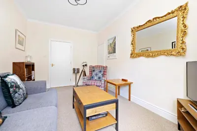 a living room with a couch and a mirror at JOIVY Modern Flat on Rose Street in Edinburgh