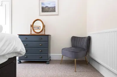 a bedroom with a blue chair and a dresser at JOIVY Modern Flat on Rose Street in Edinburgh