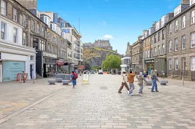 a group of people walking down a city street at JOIVY Modern Flat on Rose Street in Edinburgh