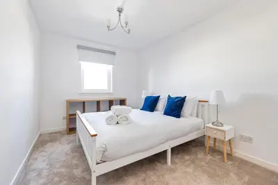 a bedroom with a white bed with blue pillows at JOIVY Modern 2 bed flat near Murrayfield Stadium in Edinburgh