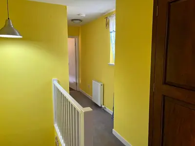 a hallway with yellow walls and a door and stairs at St John's Town of Dalry Glentress Apartment 1 in Dalry