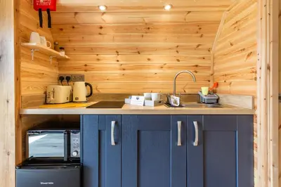 a kitchen with blue cabinets and a sink in a cabin at Kings Caves Glamping in Torbeg