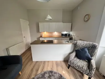 a kitchen with a counter and a couch in a room at Number 79, Cosy Central Helensburgh 1 Bedroom, ground floor pet friendly, garden in Helensburgh