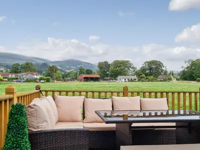 a couch on a deck with a table and a field at Castle Campbell View in Dollar