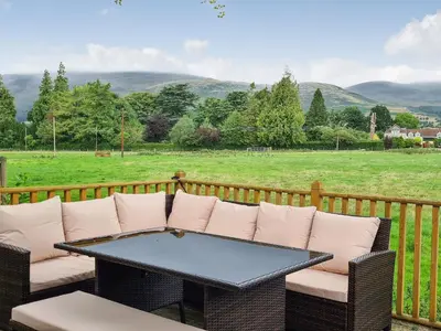 a table and chairs on a deck with a view of a field at Castle Campbell View in Dollar