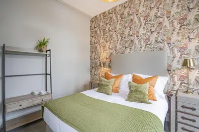 a bedroom with a bed with green and orange pillows at The Woodside in Doune