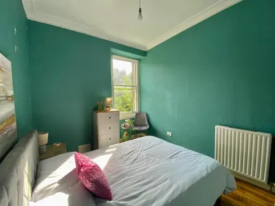 a bedroom with green walls and a bed with pink pillows at Traveller Award Winner 2024 - Edinburgh Apartment with 3 Beds in Edinburgh