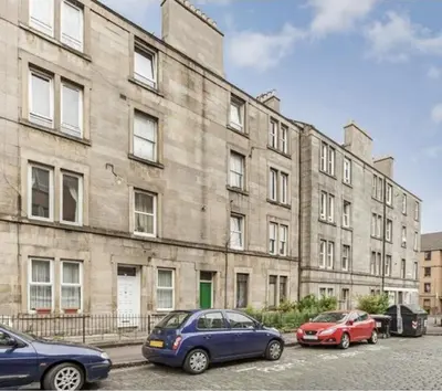 two cars parked in front of a large building at Traveller Award Winner 2024 - Edinburgh Apartment with 3 Beds in Edinburgh