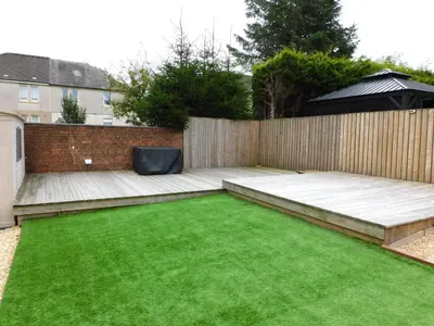 a small garden with a wooden fence and green grass at Beautiful 3 bedroom home with large garden 35 mins to Glasgow & Edinburgh in Whitburn