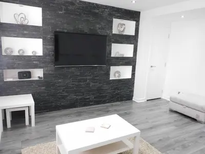 a living room with a tv on a brick wall at Beautiful 3 bedroom home with large garden 35 mins to Glasgow & Edinburgh in Whitburn