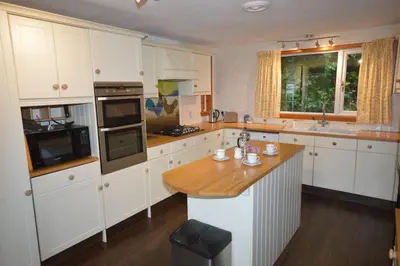 a kitchen with white cabinets and a wooden counter top at Ardura Apartment No 1 in Oban