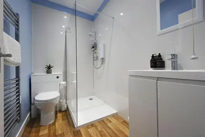 a white bathroom with a shower and a toilet at George Street Apartment in Oban