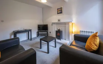 a living room with two couches and a fireplace at George Street Apartment in Oban