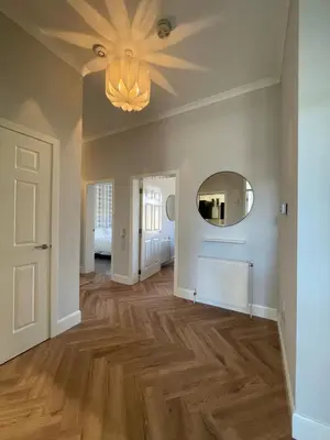 an empty living room with a mirror and wooden floors at The Haven in Greenock