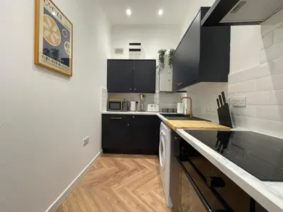 a kitchen with black cabinets and a white counter top at The Haven in Greenock