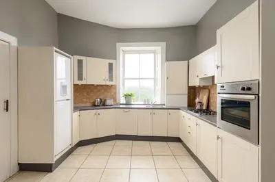 a white kitchen with white cabinets and a window at 2 Bed Old Town Apartment - Next To Castle in Edinburgh