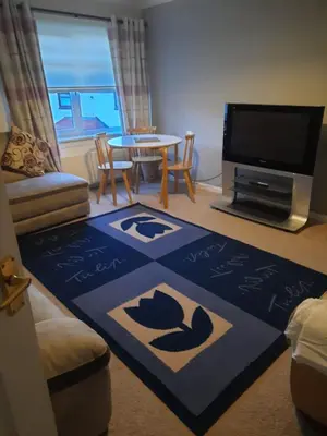 a living room with a table and a tv at Ardfern Apartments in Airdrie