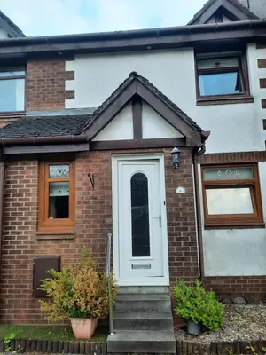 a brick house with a white door and stairs at Ardfern Apartments in Airdrie