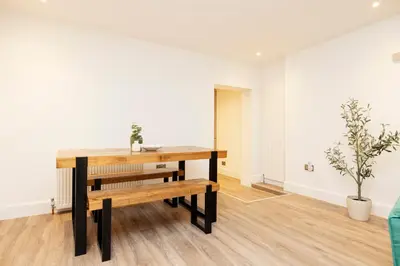 a dining room with a wooden table and benches at JOIVY 3BR Flat in Haymarket with Free Parking in Edinburgh