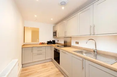a kitchen with white cabinets and a sink at JOIVY 3BR Flat in Haymarket with Free Parking in Edinburgh