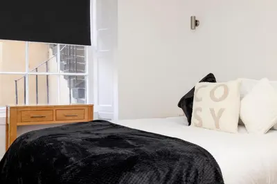 a bedroom with a bed with a black blanket on it at JOIVY 3BR Flat in Haymarket with Free Parking in Edinburgh