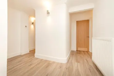 an empty room with a white wall and wooden floors at JOIVY 3BR Flat in Haymarket with Free Parking in Edinburgh