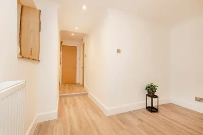 a hallway with white walls and a table with a plant at JOIVY 3BR Flat in Haymarket with Free Parking in Edinburgh