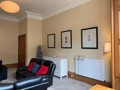 a living room with a black leather couch and pictures on the wall at JOIVY Adorable flat near West End in Edinburgh