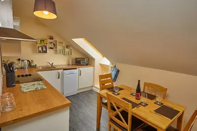 a kitchen and dining room with a wooden table and chairs at Campbells Loft in Oban