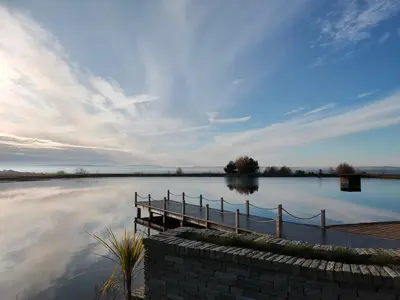 a body of water with a dock in the middle at The Log Cabins at The Vu in Bathgate