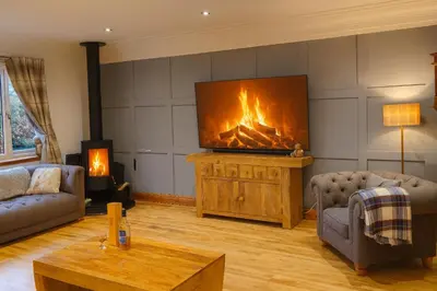 a living room with a tv and a fireplace at Gleann Fia House in Arrochar
