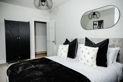 a bedroom with a large bed with black and white pillows at 2 BDR House At Caledonia Luxe Stays Short Lets & Serviced Accommodation Crieff in Crieff