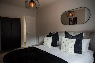 a bedroom with a bed with black and white pillows at 2 BDR House At Caledonia Luxe Stays Short Lets & Serviced Accommodation Crieff in Crieff