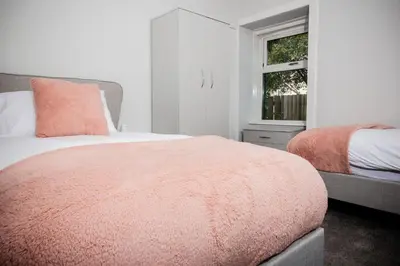 a bedroom with a bed with a pink blanket and a window at 2 BDR House At Caledonia Luxe Stays Short Lets & Serviced Accommodation Crieff in Crieff