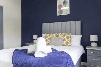 a bedroom with a bed with a blue wall at Raploch House in Larkhall