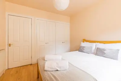 a bedroom with a large white bed with a wooden headboard at Amazing Castle View Apartment in Edinburgh