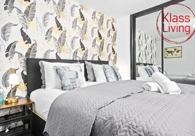 a bedroom with a king sized bed with a tropical wallpaper at Rothesay House by Klass Living Coatbridge in Coatbridge