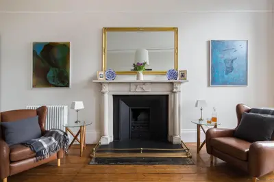 a living room with two chairs and a fireplace at Magnificent Georgian 3-Bedroom Apartment in New Town in Edinburgh