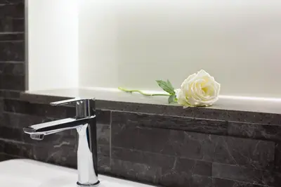 a bathroom sink with a white rose sitting on a ledge at Magnificent Georgian 3-Bedroom Apartment in New Town in Edinburgh